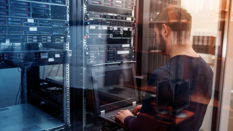 young it engeneer business man with thin modern aluminium laptop in network server room