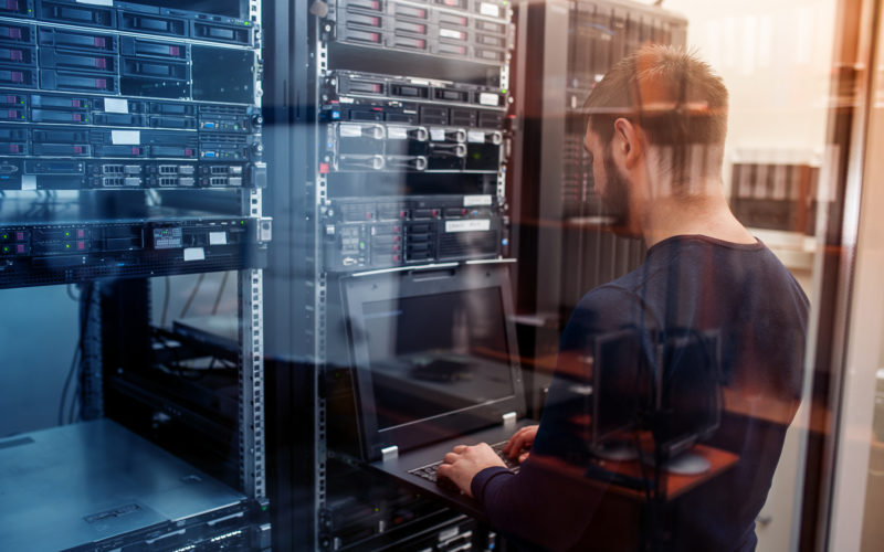 young it engeneer business man with thin modern aluminium laptop in network server room